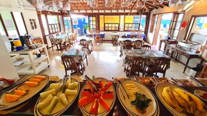A restaurant with multiple tables and chairs, serving fruit and other dishes. - Pousada Solar de Geribá (Búzios)
