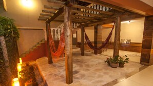 A wooden pergola with hammocks, a staircase, and a tiled floor with potted plants. - Pousada Solar de Geribá (Búzios)