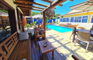Um deck de madeira com piscina, móveis de exterior e um muro de pedra.