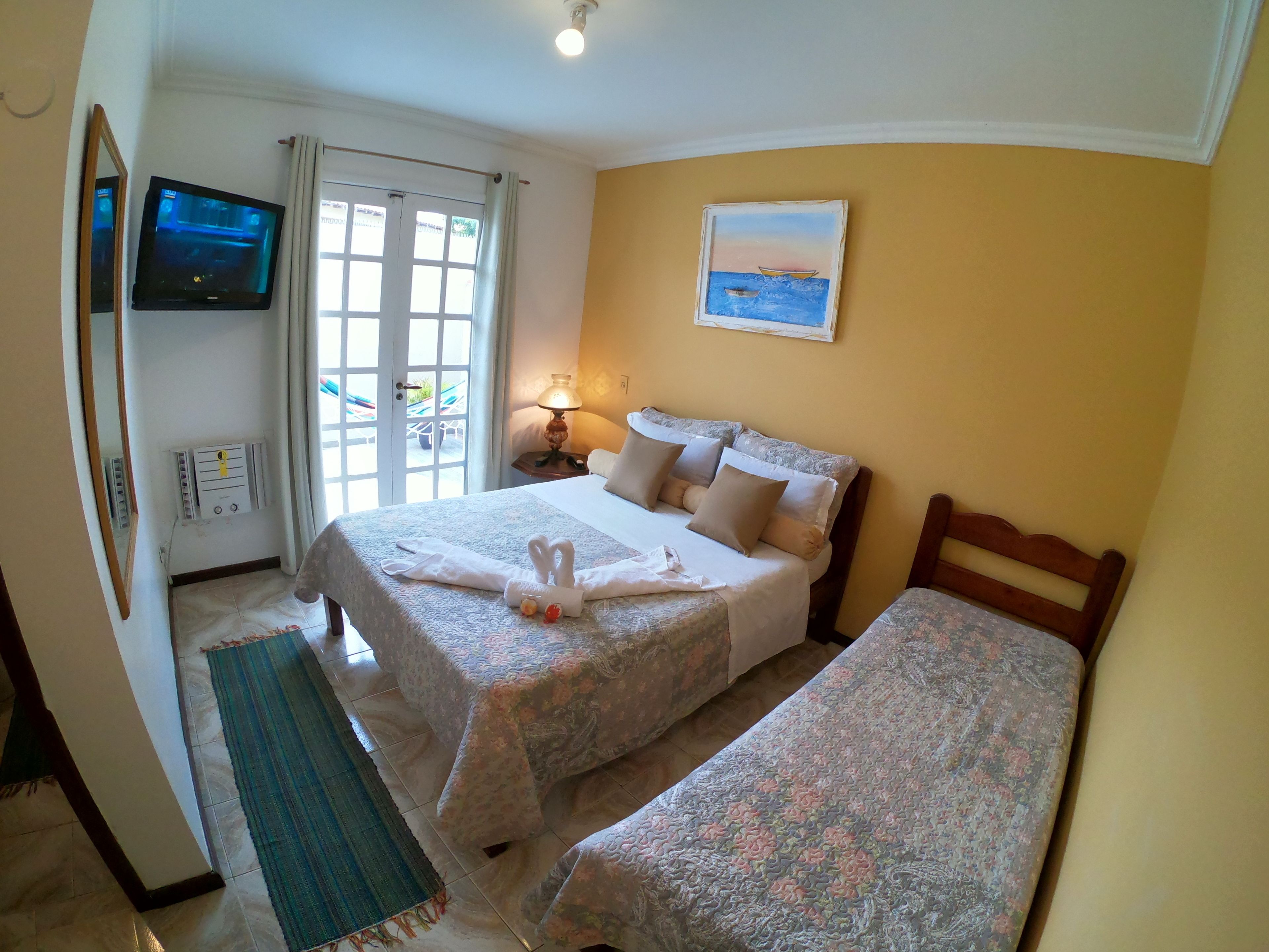 Ein Hotelzimmer mit Bett, Fernseher, einem Gemälde und einem Fenster mit Vorhängen.