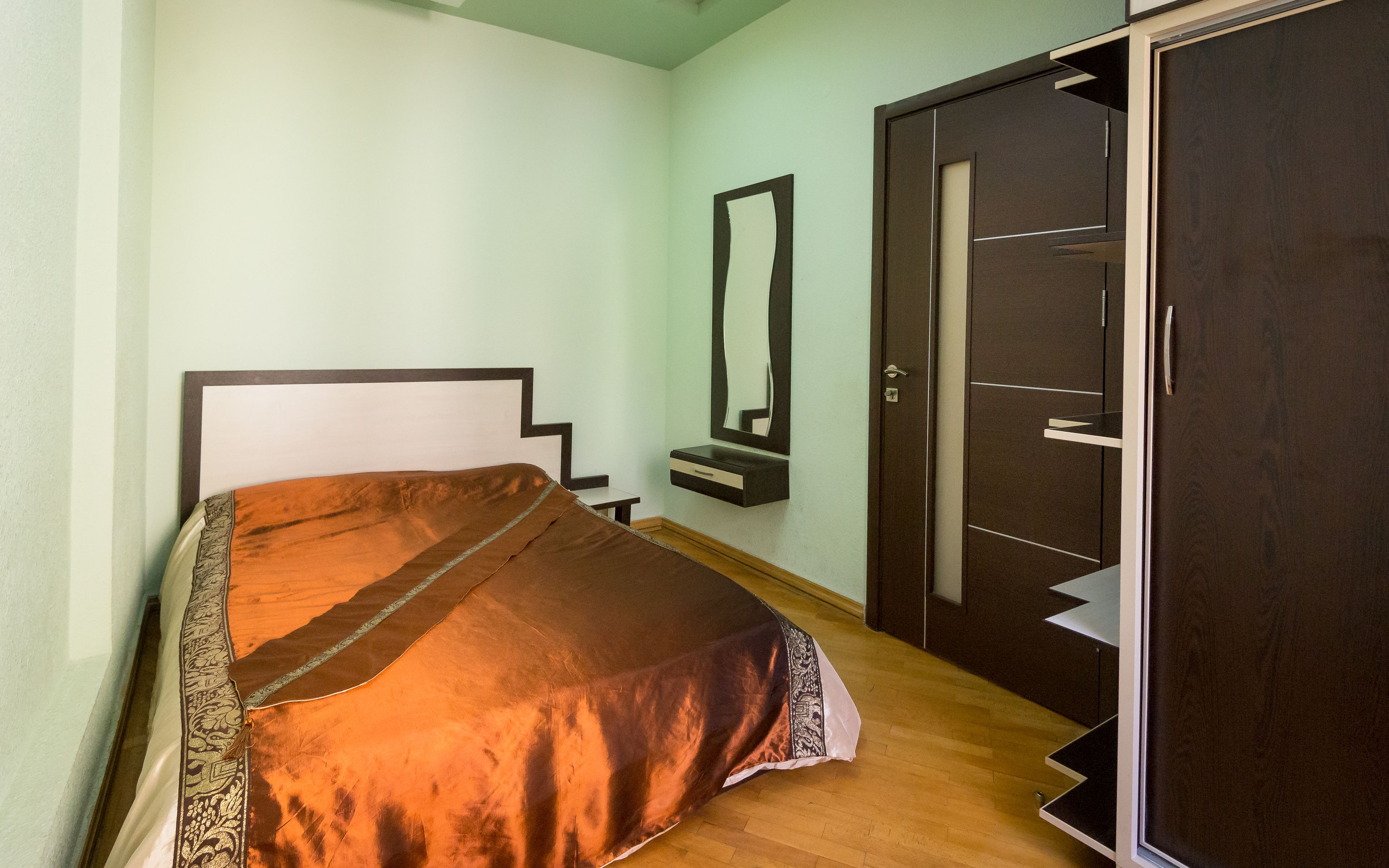 Un dormitorio con cama, mesita de noche, espejo y armario.