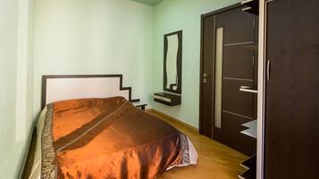 Un dormitorio con cama, mesita de noche, espejo y armario.