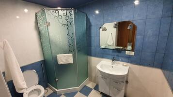 A bathroom with a toilet, a glass shower enclosure, a sink with a mirror, and blue and white checkered flooring.