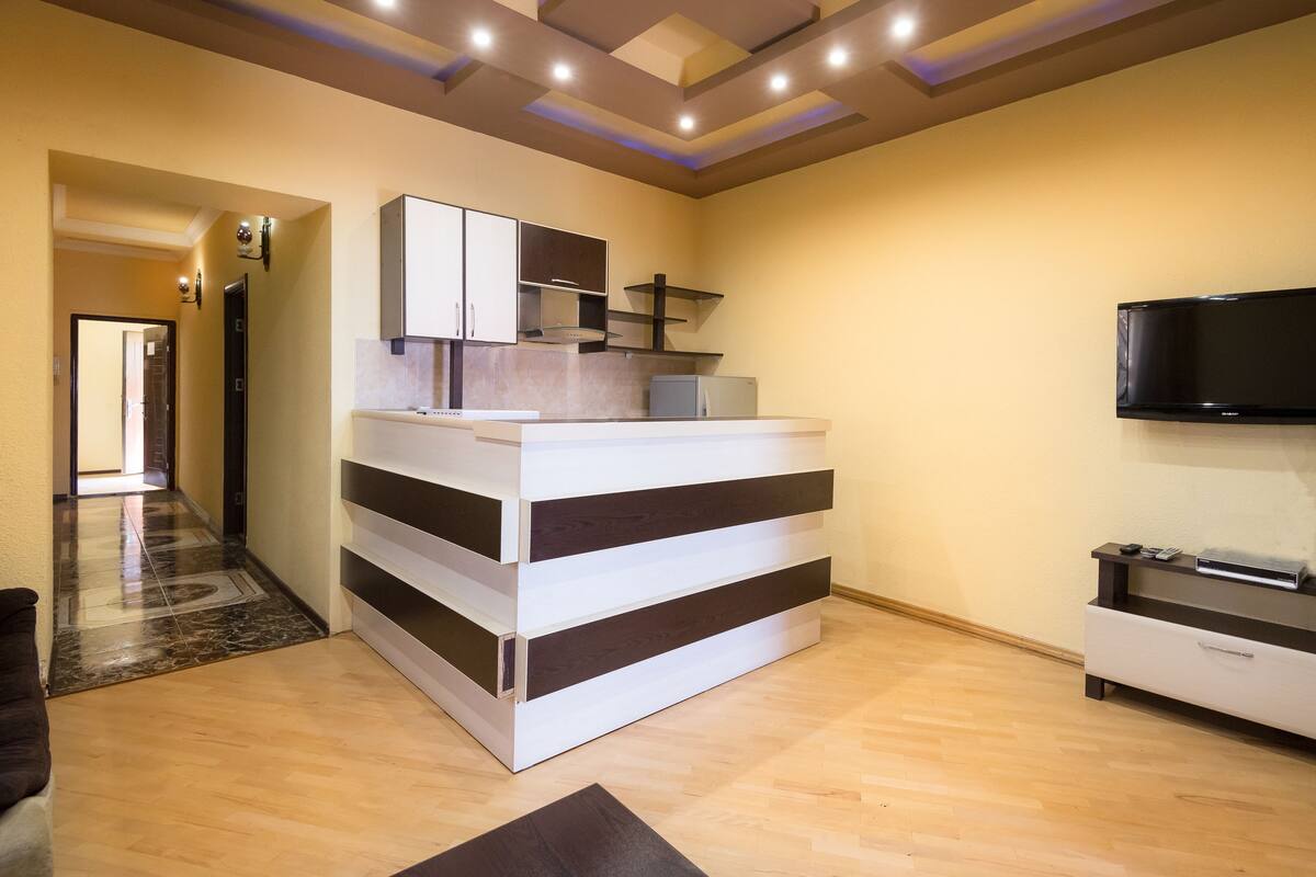 A modern kitchen with a built-in refrigerator, a microwave, and a flat-screen TV mounted on the wall.