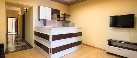 A modern kitchen with a built-in refrigerator, a microwave, and a flat-screen TV mounted on the wall.