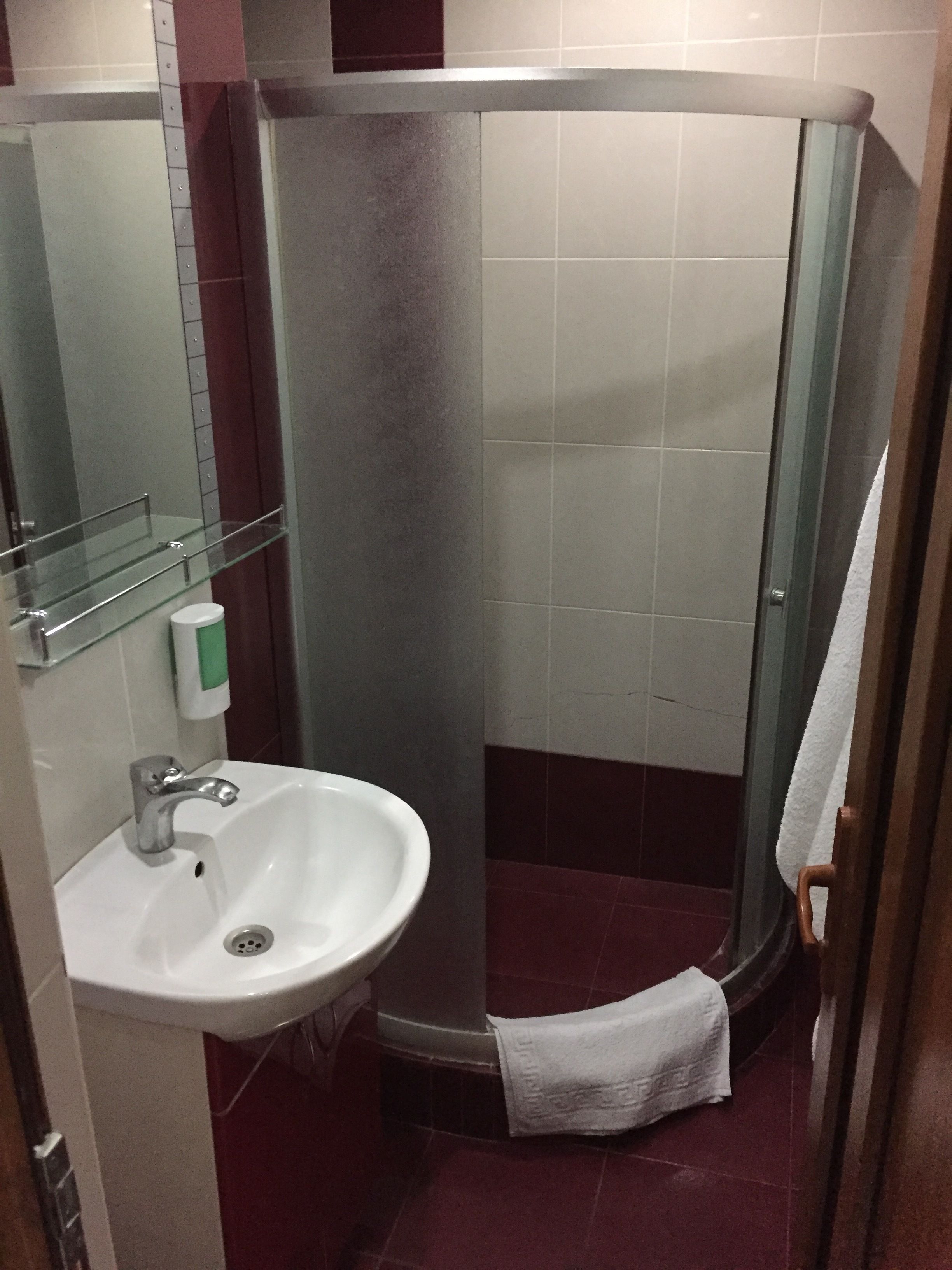 Une salle de bain avec un lavabo blanc, une étagère en verre et un espace douche.