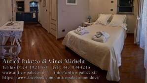 A hotel room with a bed, bedside table, and a small kitchenette. - Antico Palazzo (Mondovi)