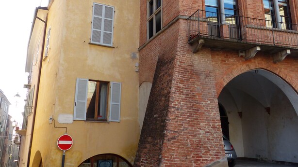 A historic building with a yellow facade and red brick arches. - Antico Palazzo (Mondovi)