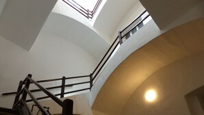 A staircase with a wooden handrail and a glass balustrade, leading to an upper floor. - Antico Palazzo (Mondovi)