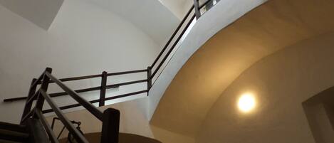 A staircase with a wooden handrail and a glass balustrade, leading to an upper floor.