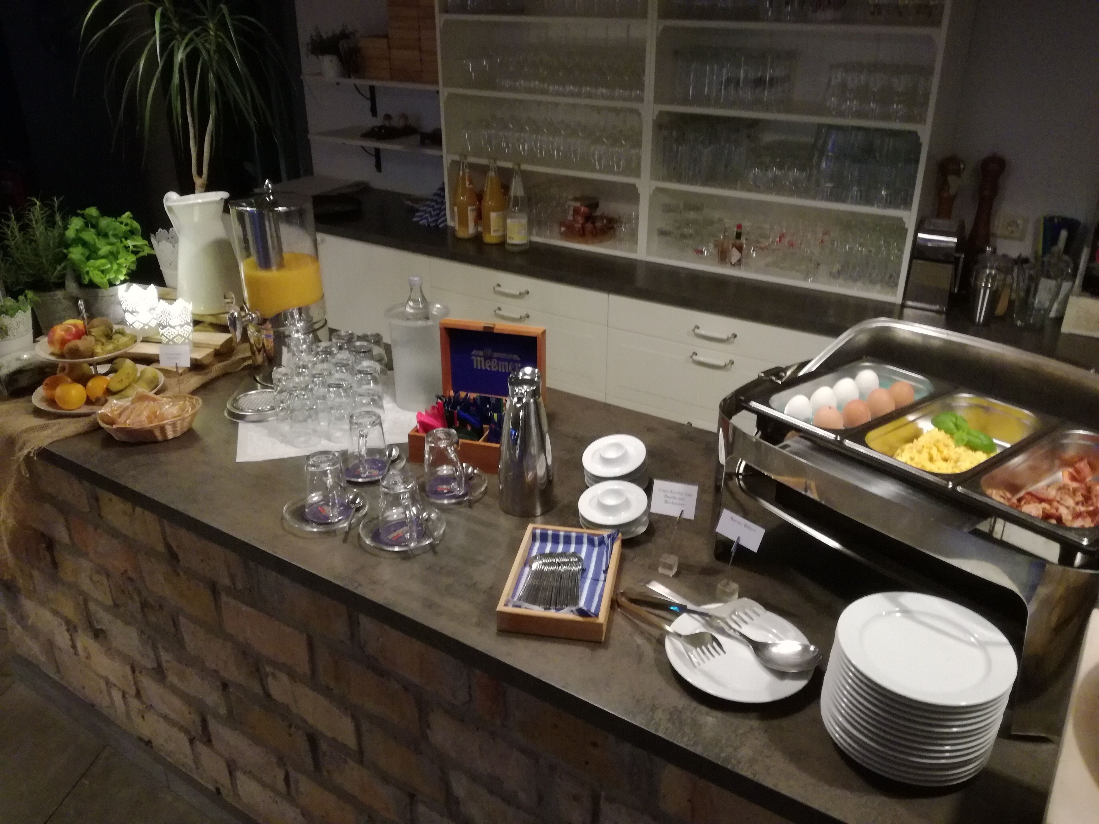 A buffet setup with various food items, utensils, and glassware.