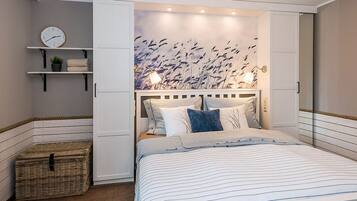 Un dormitorio con cama, mesita de noche, reloj y estante en la pared con una planta.