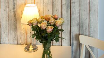 Et bord med en lampe og en vase med blomster foran en trævæg med et ur.
