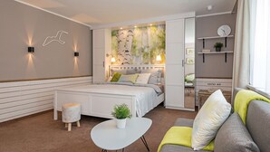 Ein modernes Schlafzimmer mit einem Bett, Nachttischen, einem Sofa und einem kleinen Tisch mit einer Pflanze.