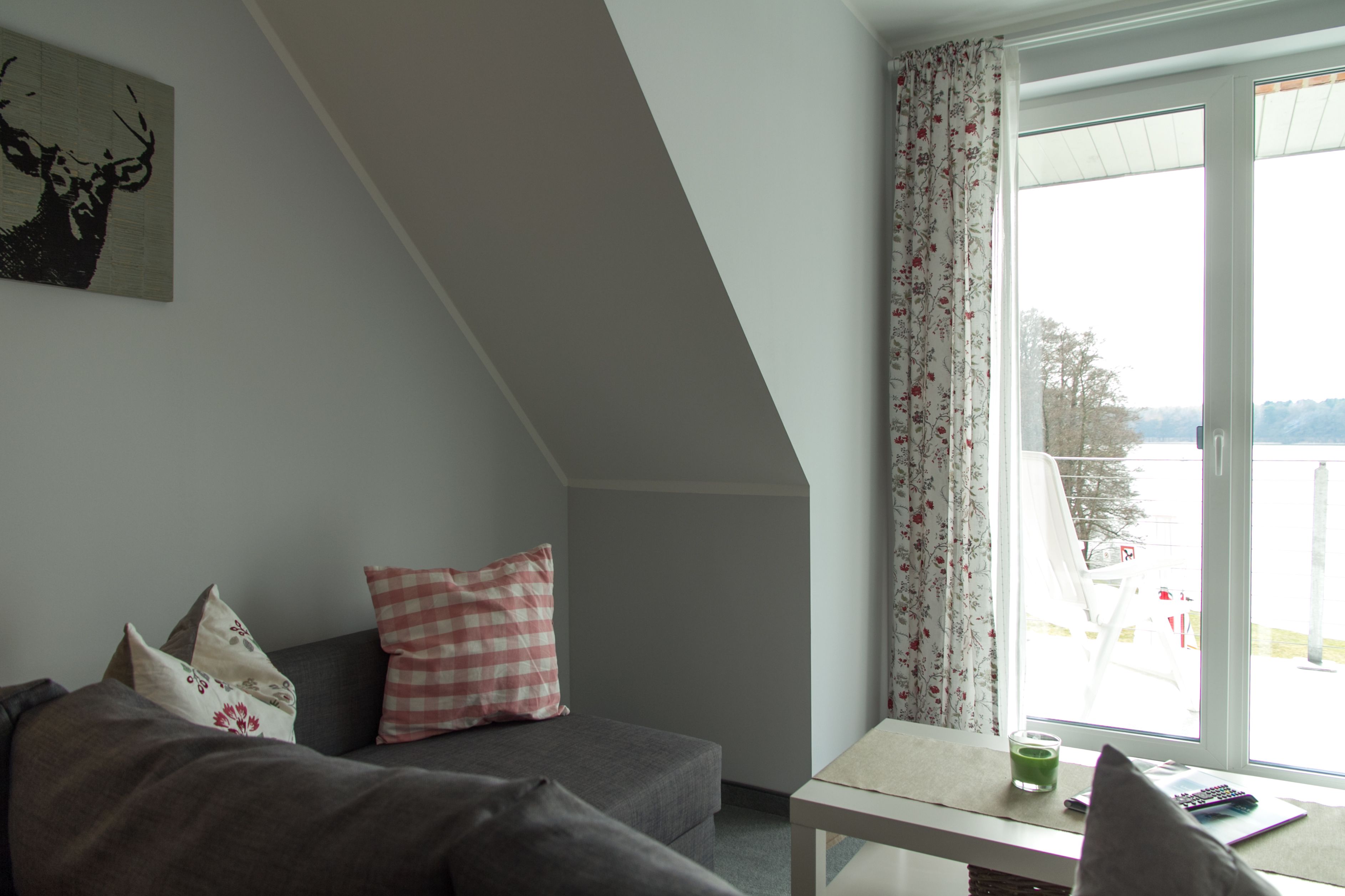 A cozy living room with a gray sofa, a checkered pillow, and a painting of a deer.