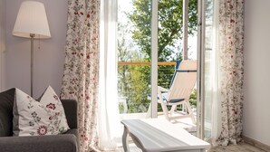 Ein Zimmer mit einer Sitzecke, einem Tisch und einem Stuhl neben einer Schiebetür, die auf einen Balkon führt.