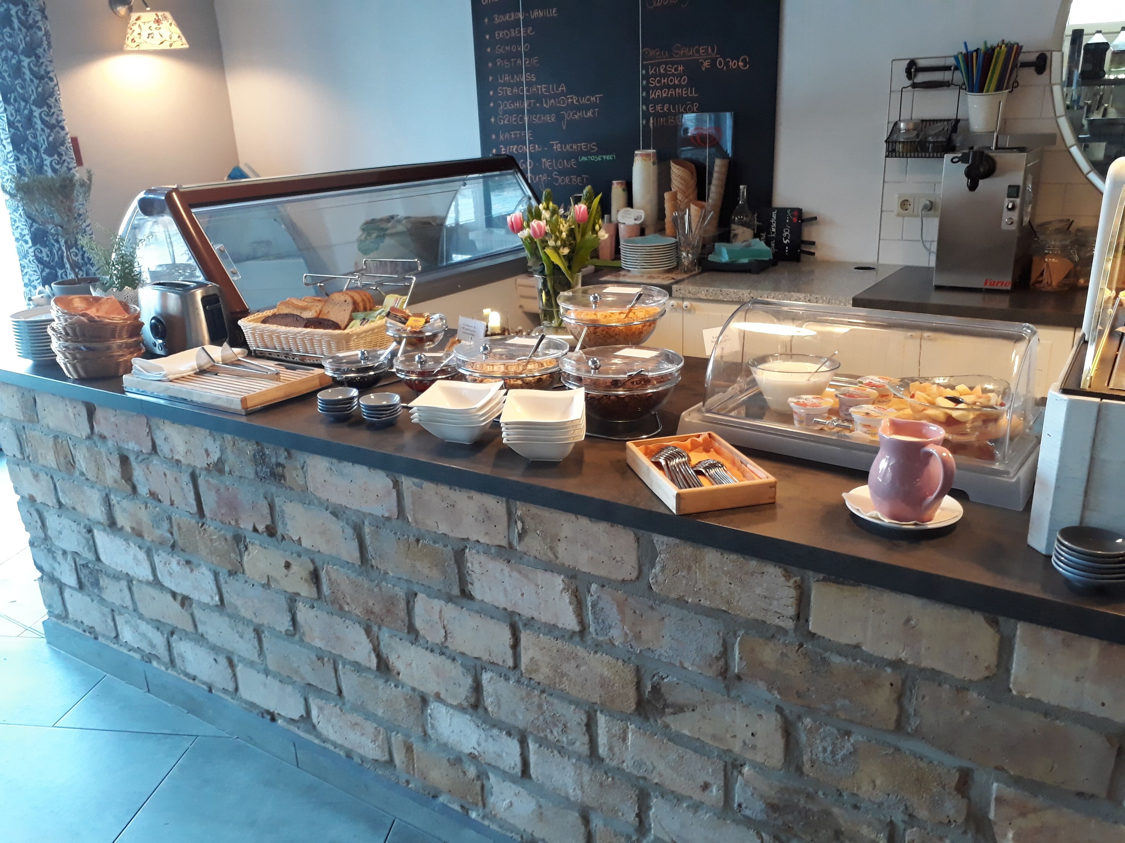A buffet counter with various food items, a coffee machine, and a chalkboard menu.