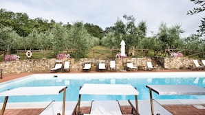 A pool area with lounge chairs and a stone wall. - I Greppi di Silli (San Casciano in Val di Pesa)