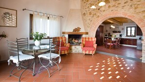 A rustic interior with a stone wall, a fireplace, and a dining area with chairs and a table. - I Greppi di Silli (San Casciano in Val di Pesa)
