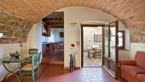A rustic interior with a stone archway leading to a dining area and a kitchen. - I Greppi di Silli (San Casciano in Val di Pesa)