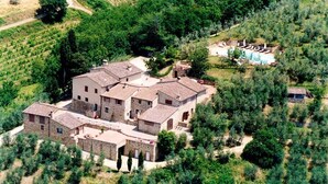 An aerial view of a stone building with multiple rooms, surrounded by vineyards and a swimming pool area. - I Greppi di Silli (San Casciano in Val di Pesa)