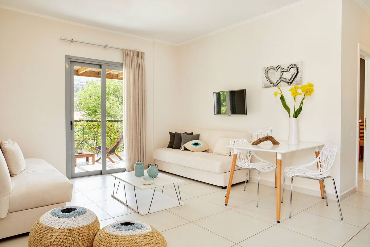 A modern living room with a sofa, coffee table, and chairs. There is a sliding glass door leading to an outdoor area.