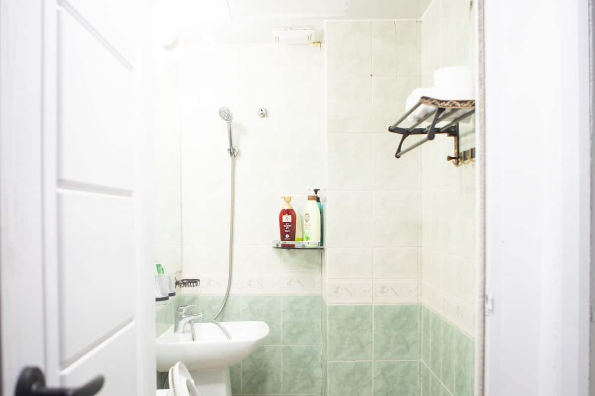 A small bathroom with a toilet, sink, and shower.