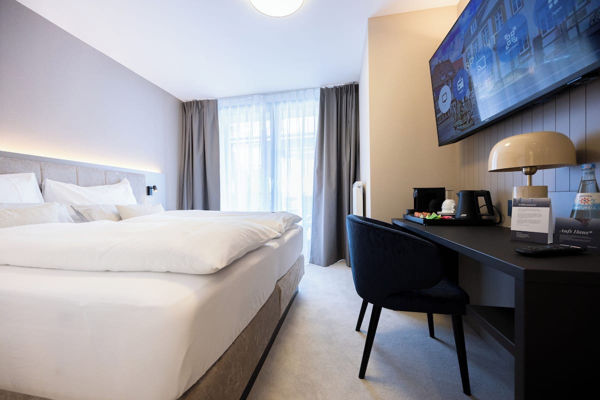 A hotel room with a bed, a desk with a chair, a flat-screen TV, and a coffee maker.