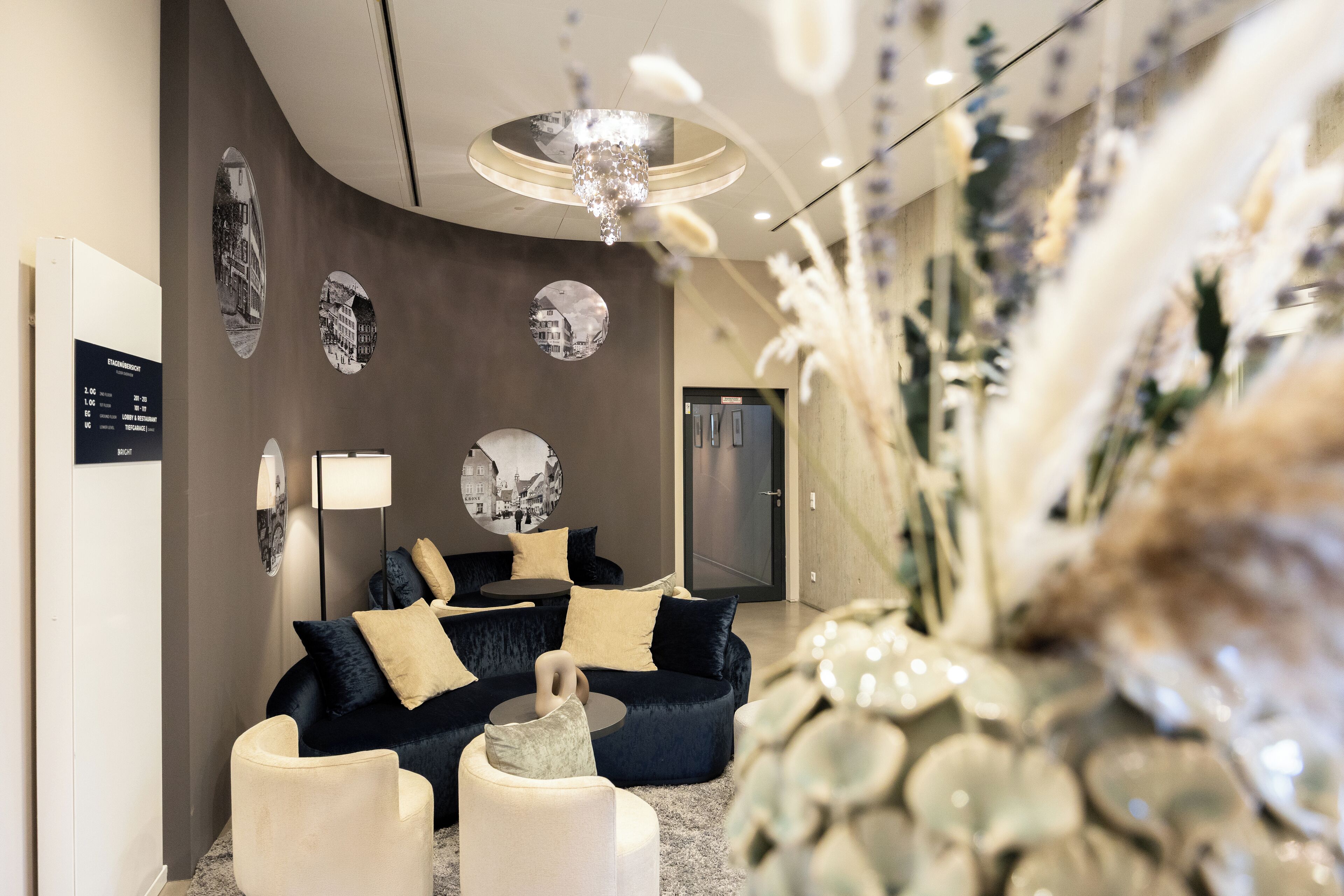A modern interior with a dark blue sofa set, a round coffee table, and a decorative mirror on the wall.
