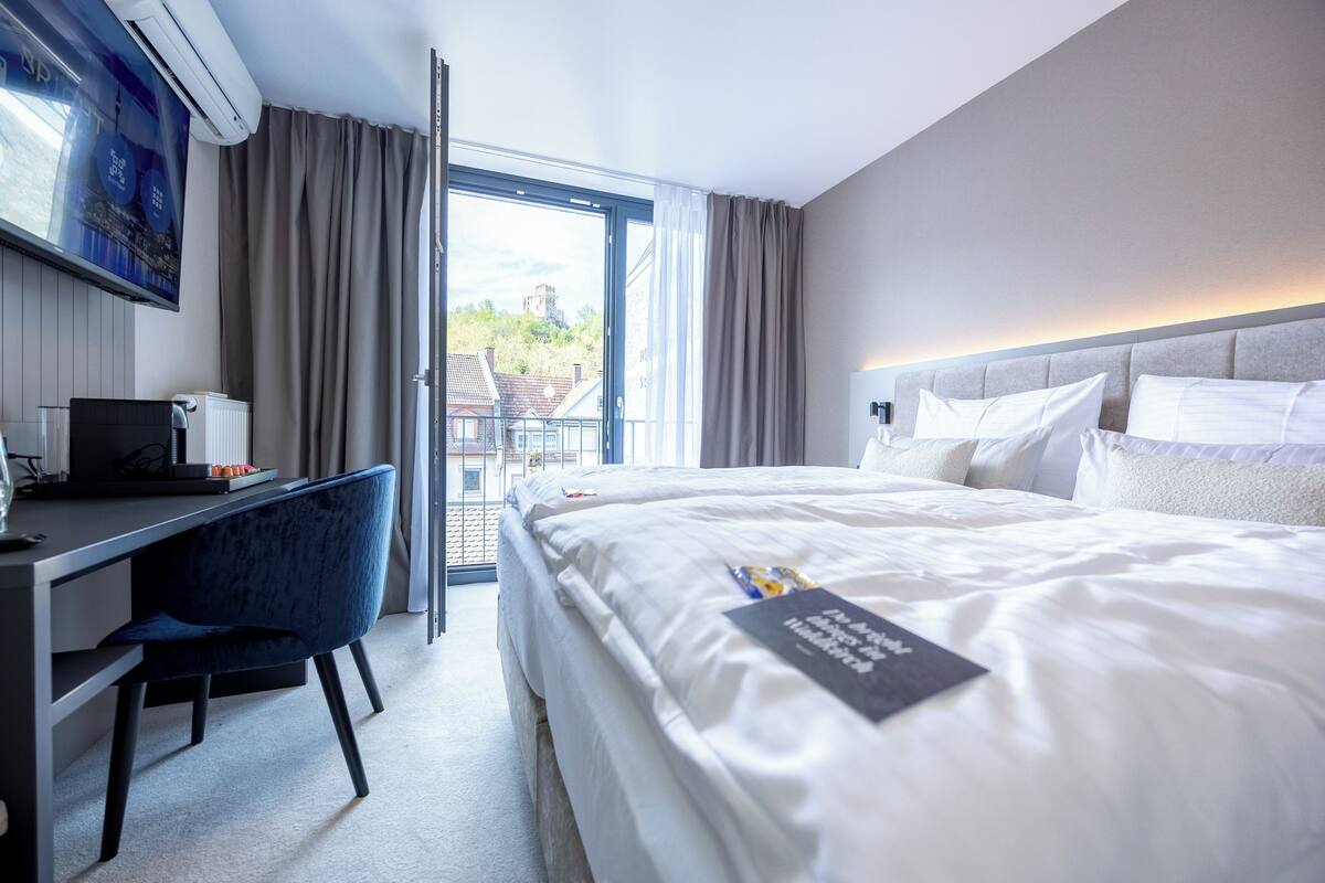 A hotel room with a bed, a desk, a chair, and a TV.