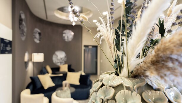 A modern living room with a dark blue sofa, white armchairs, and a decorative vase with plants. - Digital Hotel Kronjuwel by BRIGHT Waldkirch - Self Check-in (Waldkirch)