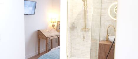 A modern bathroom with a glass-enclosed shower, a round mirror, and a wooden cabinet.