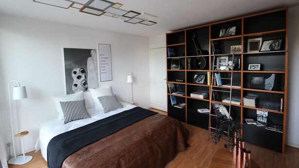 Une chambre moderne avec un grand lit, une bibliothèque et un luminaire au plafond original.