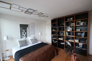 Une chambre moderne avec un grand lit, une bibliothèque et un luminaire au plafond original.