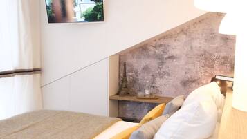 A bedroom with a bed, pillows, a TV, and a lamp.