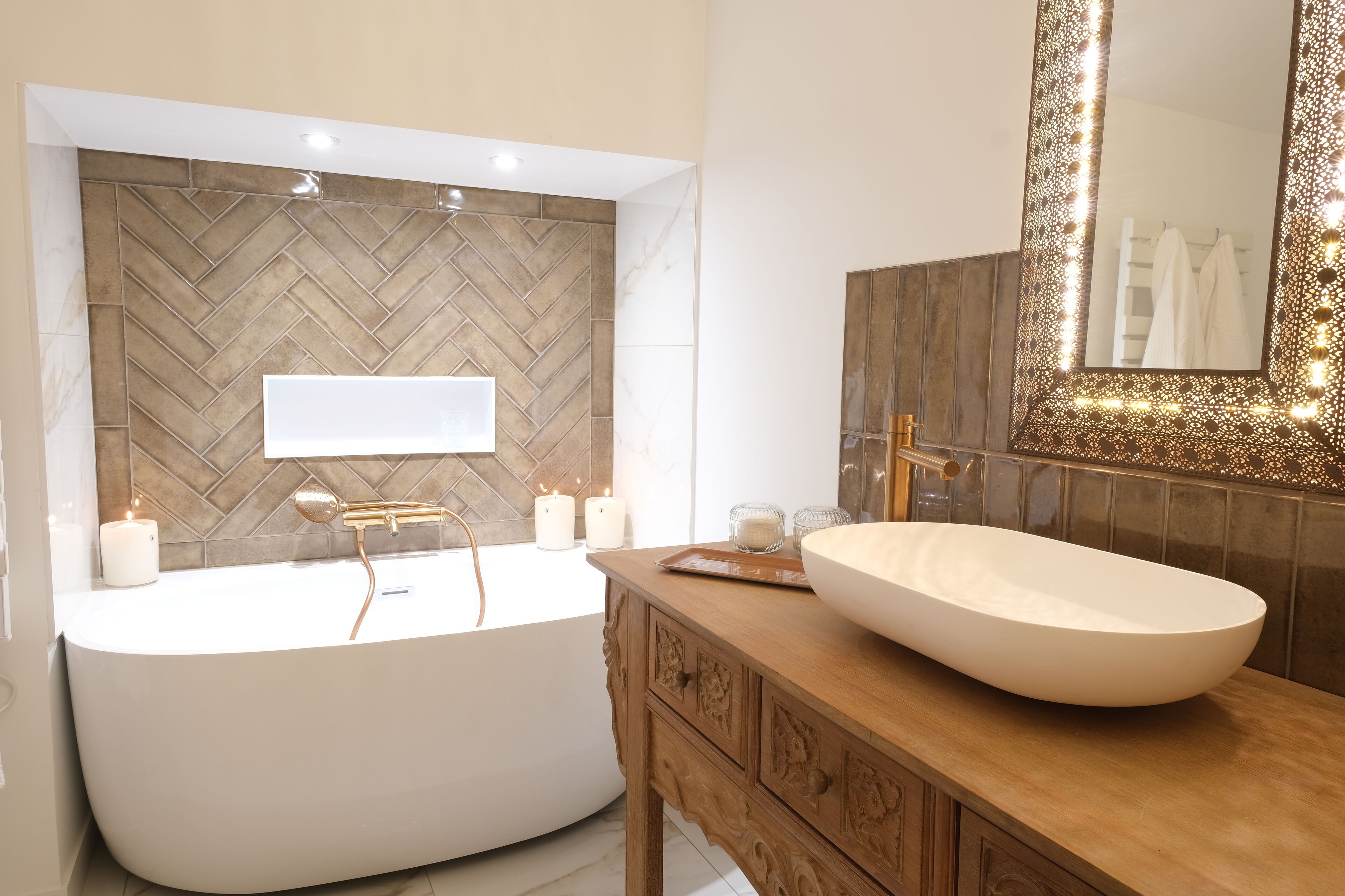 Une salle de bain moderne avec une baignoire sur pieds, un meuble-lavabo en bois et un grand miroir doté d’un cadre décoratif.
