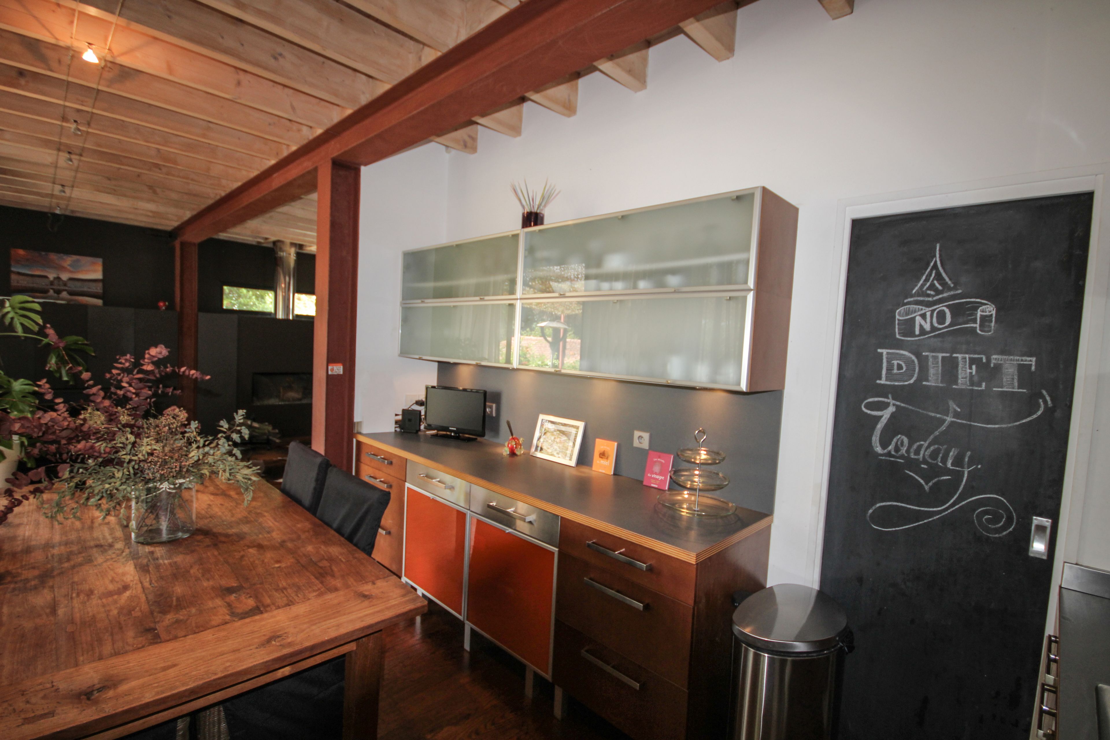 A modern kitchen with wooden cabinets, a glass-fronted island, and a chalkboard with 'NO DIET Today' written on it.