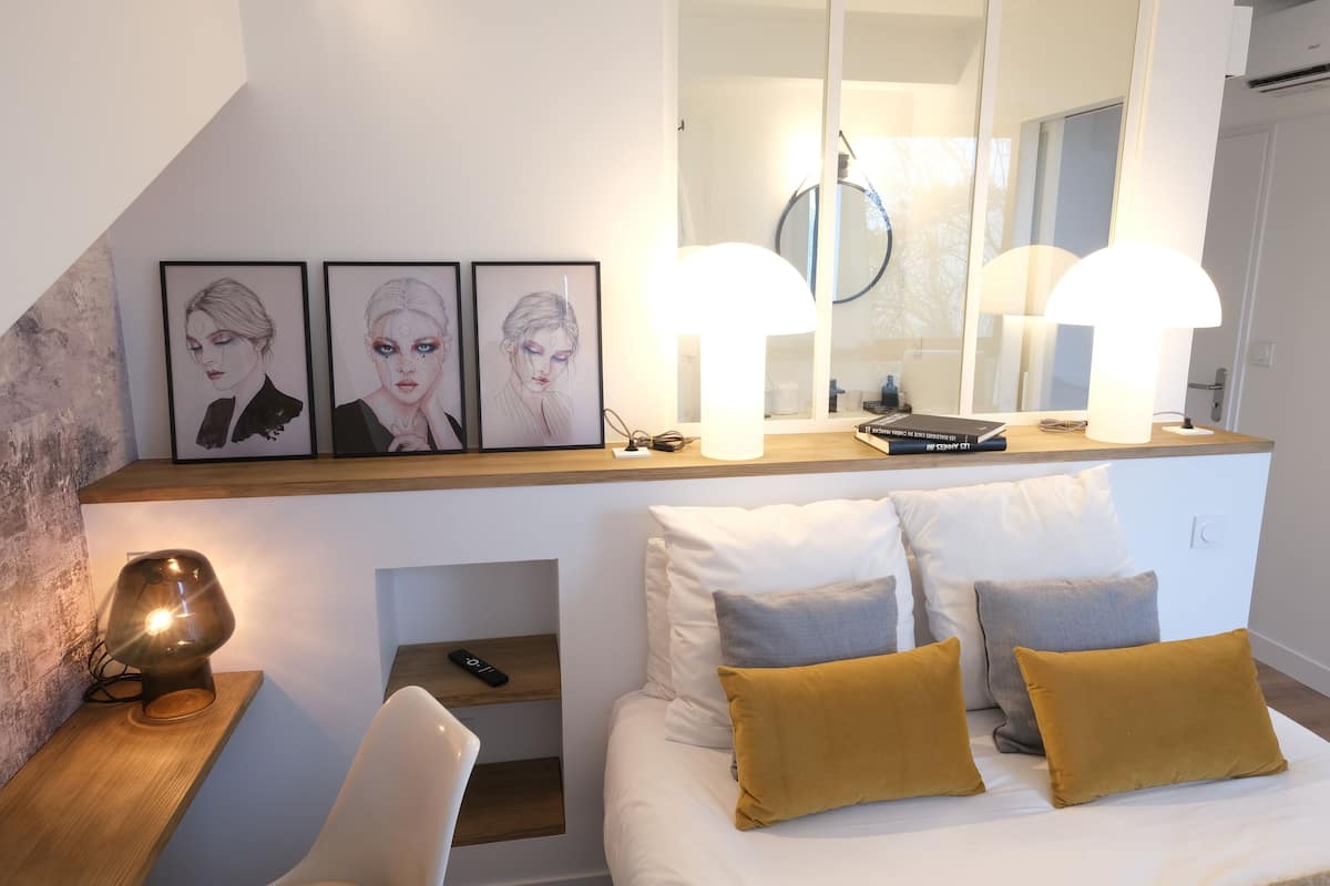 Un dormitorio moderno con cama, mesitas de noche, un espejo y cuadros en la pared.