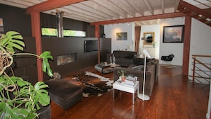 Un salon moderne avec un plancher en bois, une grande fenêtre, une cheminée et un escalier.