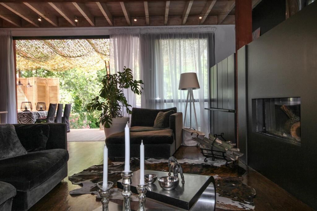 A modern living room with a dark sofa, a glass coffee table, and a fireplace.