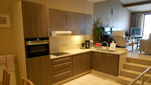 A modern kitchen with wooden cabinets, a built-in oven, and a coffee machine. - Holiday Home 't Regulierenhuisje (Tongeren)