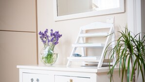 A white vanity with a mirror, a vase with purple flowers, and a potted plant. - Holiday Home 't Regulierenhuisje (Tongeren)