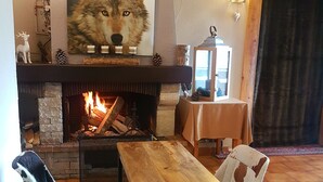 Una sala acogedora con chimenea, una mesa de comedor de madera y dos sillones estampados.