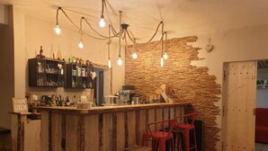 Zona de bar con mostrador de madera rústica, taburetes y pared de ladrillo.
