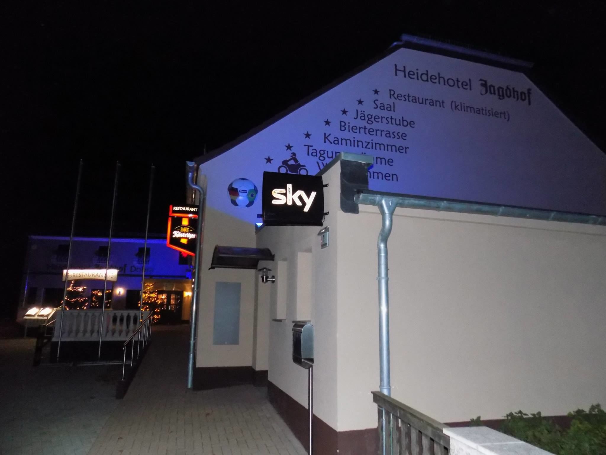Een gebouw met een bord waarop faciliteiten staan vermeld, zoals een restaurant, sauna en fitnessruimte.