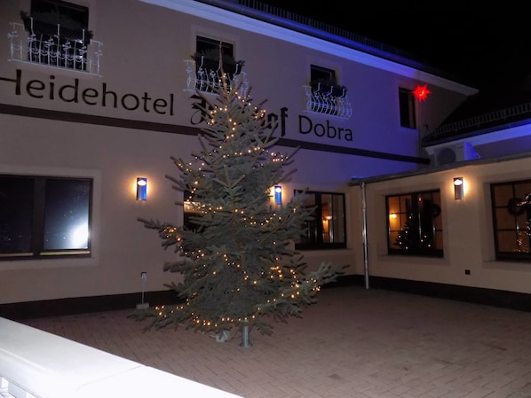 A hotel with a Christmas tree in the courtyard, illuminated by string lights. - Heidehotel Jagdhof Dobra GmbH (Bad Liebenwerda)