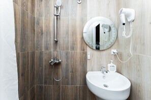 Un baño con pared de ducha de madera, un espejo redondo, un lavabo blanco y un secador de pelo en la pared.