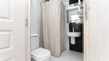 A bathroom with a toilet, a shower curtain, and a sink.