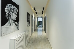 A hallway with artwork on the walls, a radiator, and a view into another room. - Alex Hotel (Yerevan)