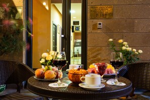 Een gedekte tafel met fruit, wijnglazen en een pompoen als middelpunt, wat een eetgedeelte met uitzicht op de hotelentree suggereert.